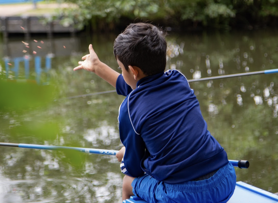 A child throws bait into a fishing lake at Get Hooked on Fishing, Ealing